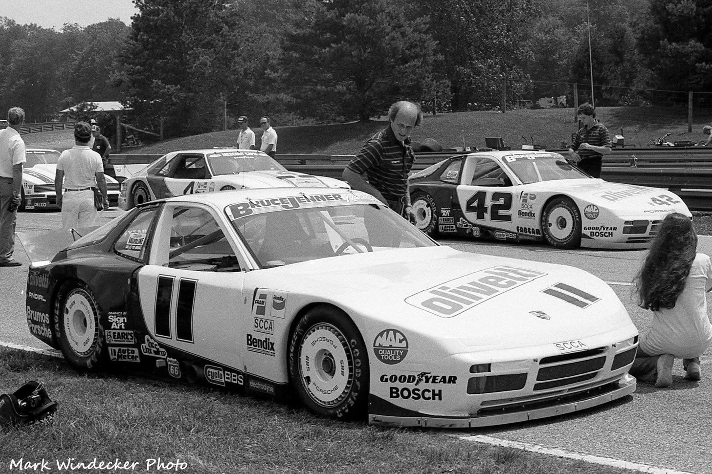 The #11 Porsche 944 in the paddock with Bruce Jenner's #42 behind and a #4 Mercury Capri, all Olivetti and Bruce Jenner Racing
