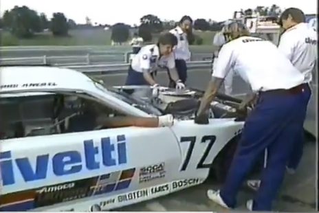 Crew working under the open bonnet of the #72 in pit lane